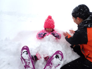 スノーシューを履いて雪に埋まる子供